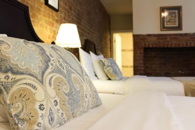 Close-up of two beds & brick wall in a room at Hotel St. Pierre