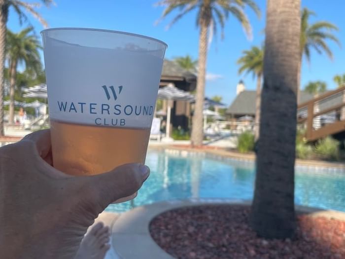 Camp Creek Inn guest holding up a Watersound Club glass of rose while lounging by the pool