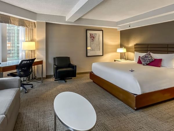 Hotel bedroom with bed, sofa bed, TV, and table