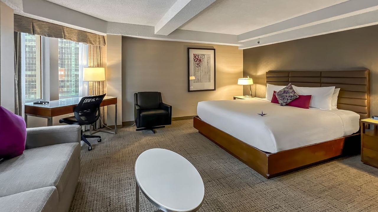 Hotel bedroom with bed, sofa bed, TV, and table