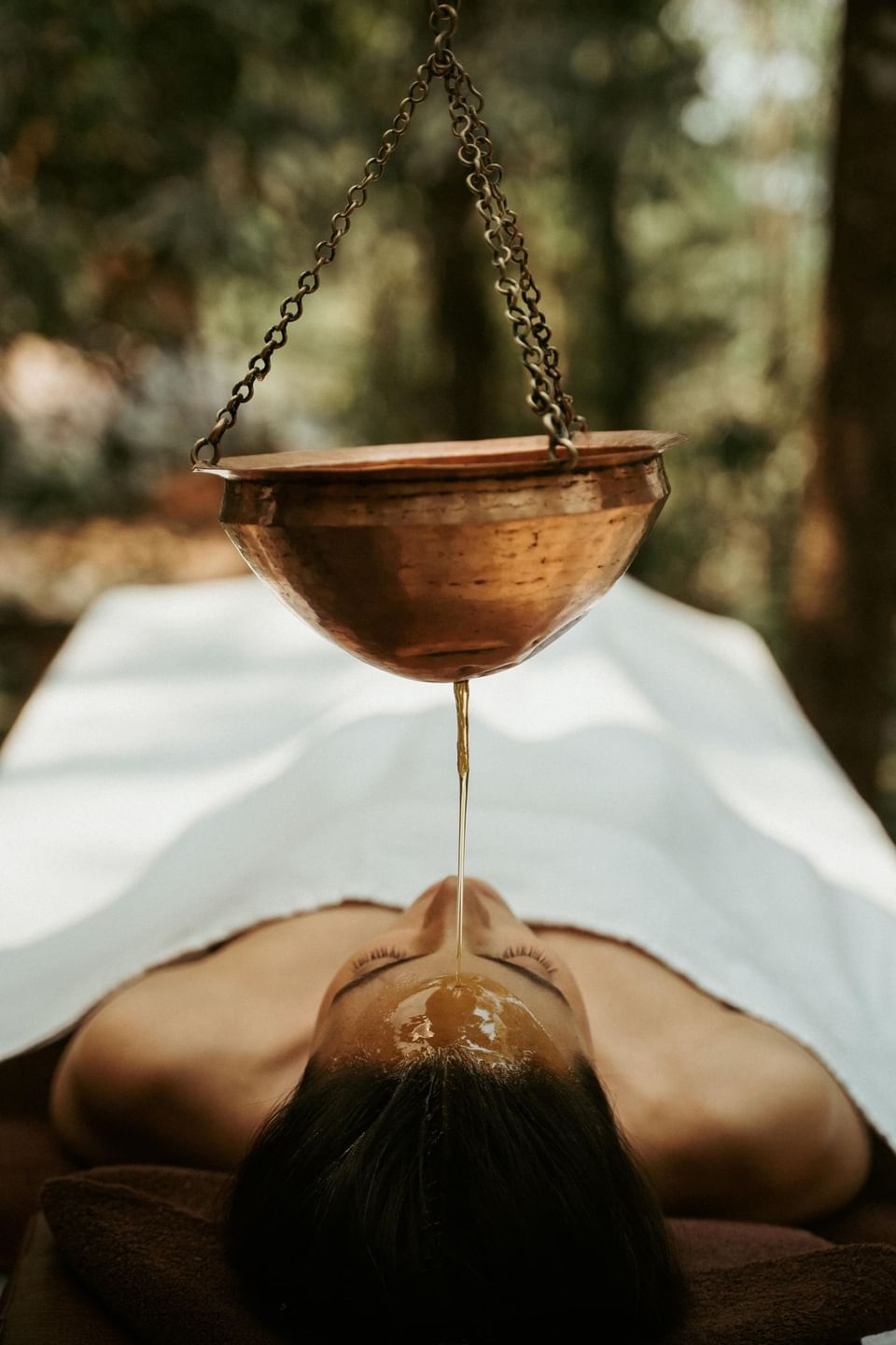 Woman receives a warm oil head treatment in a natural setting at The Dwarika's Himalayan Wellbeing