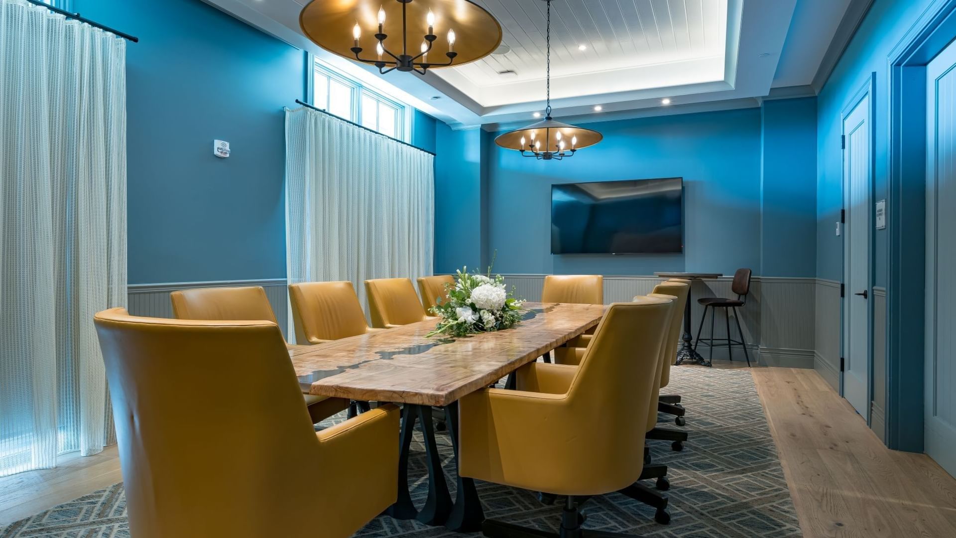 Boardroom with blue walls, wooden table, gold chairs, and modern lighting at Camp Creek Inn in Inlet Beach.