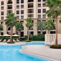 Pool with sun lounges & the hotel exterior of Palazzo Versace
