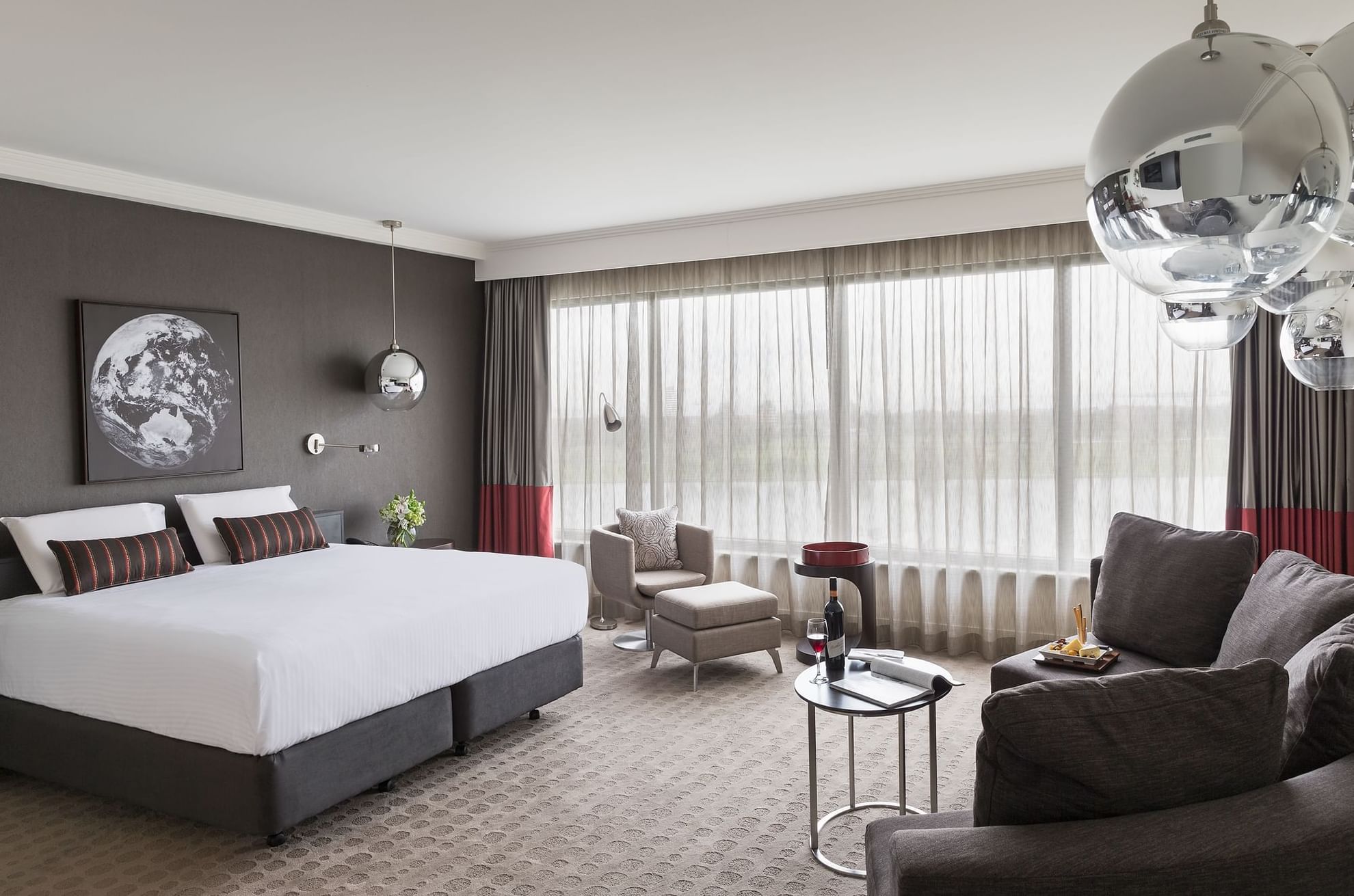 King bed and seating area in Deluxe Room with carpeted floors at Pullman Albert Park