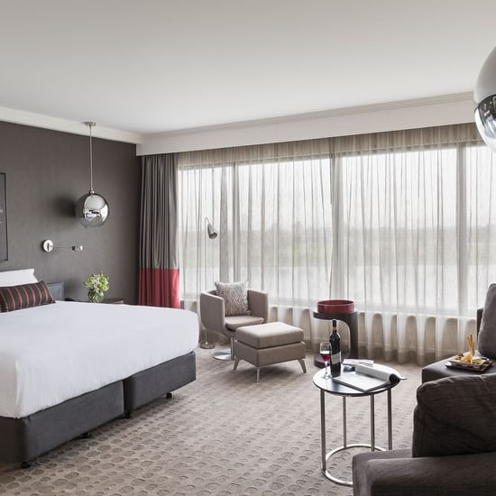 King bed and seating area in Deluxe Room with carpeted floors at Pullman Albert Park