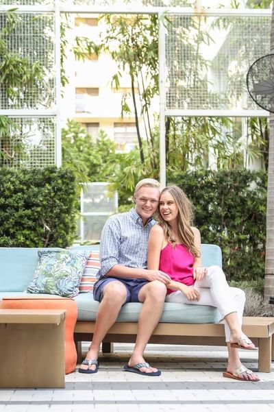 A couple posing for a picture outdoors on a cozy couch at Fairwind Hotel Miami