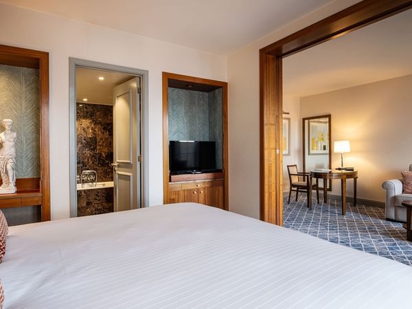 Bedroom with large bed, sofa, and bathroom at Warwick Grand-Place Brussels.