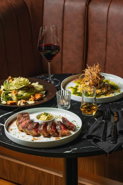 Close-up of wine glasses and various dishes served with fork and knife at The Delegate Hotel