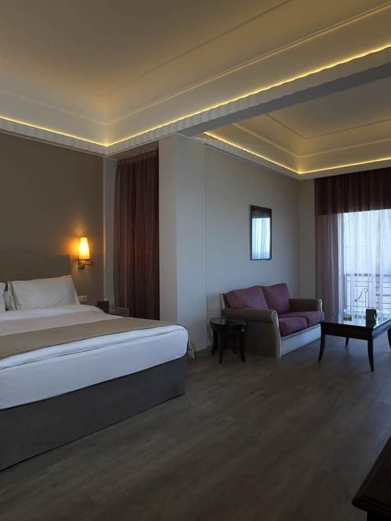 Bed with side tables and a sofa by the window in the Senior Suite at Warwick Palm Beach Hotel