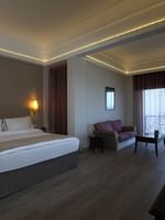 Bed with side tables and a sofa by the window in the Senior Suite at Warwick Palm Beach Hotel