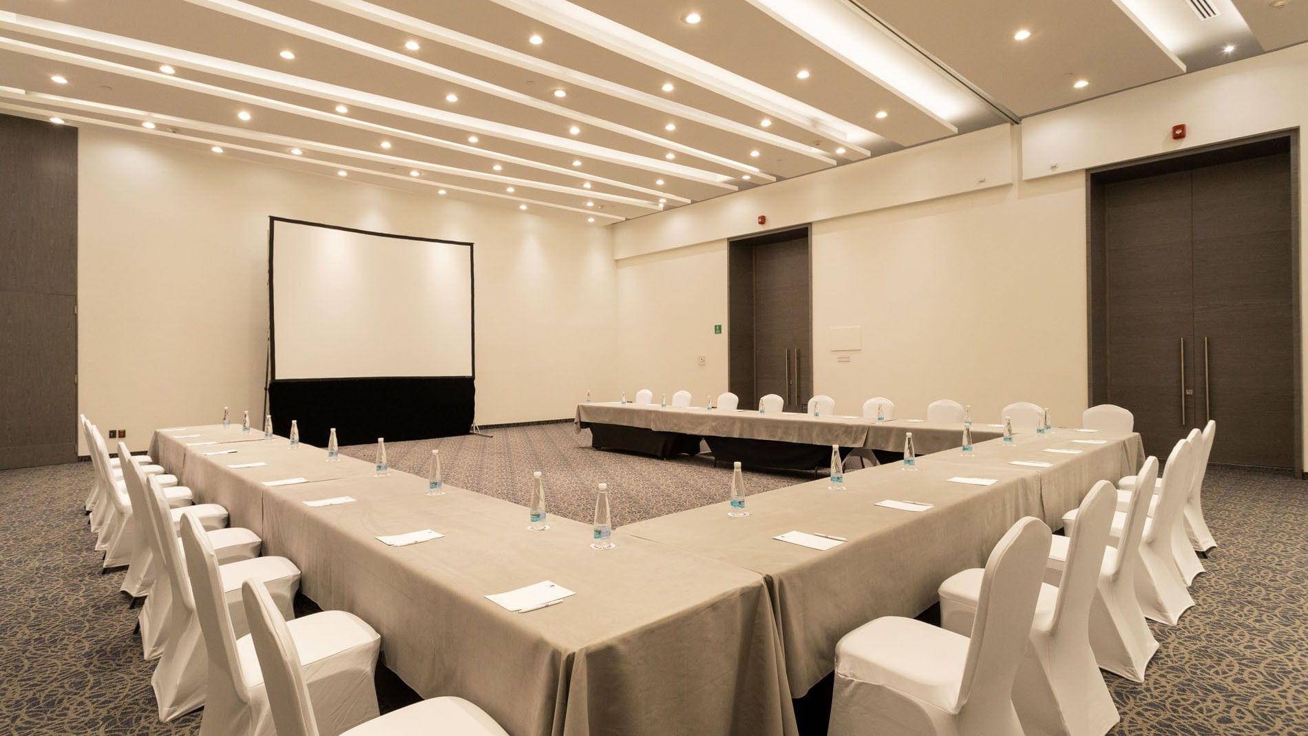 Niza room with U-shaped table setup and a large projection screen at Camino Real Fashion Drive, Monterrey