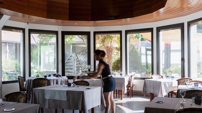 A waitress arranging a dining table at Le Logis d'Elbee