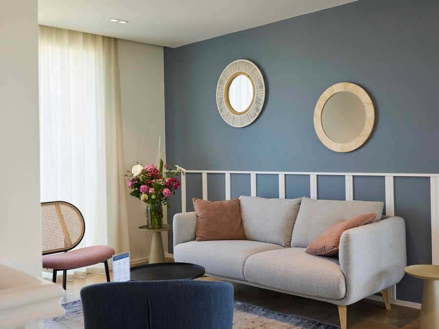 Salon élégant avec canapé, deux chaises, et deux miroirs muraux décoratifs à l'Hôtel La Marébaudière.