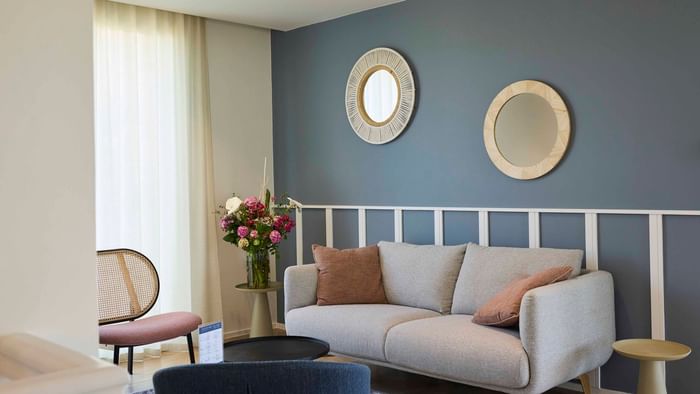 Salon élégant avec canapé, deux chaises, et deux miroirs muraux décoratifs à l'Hôtel La Marébaudière.