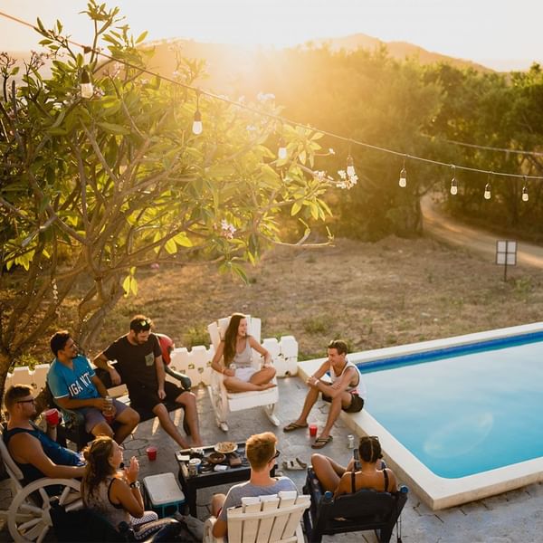 Group of people enjoying a sunset by a pool in a rustic setting at Falkensteiner Hotels & Residences