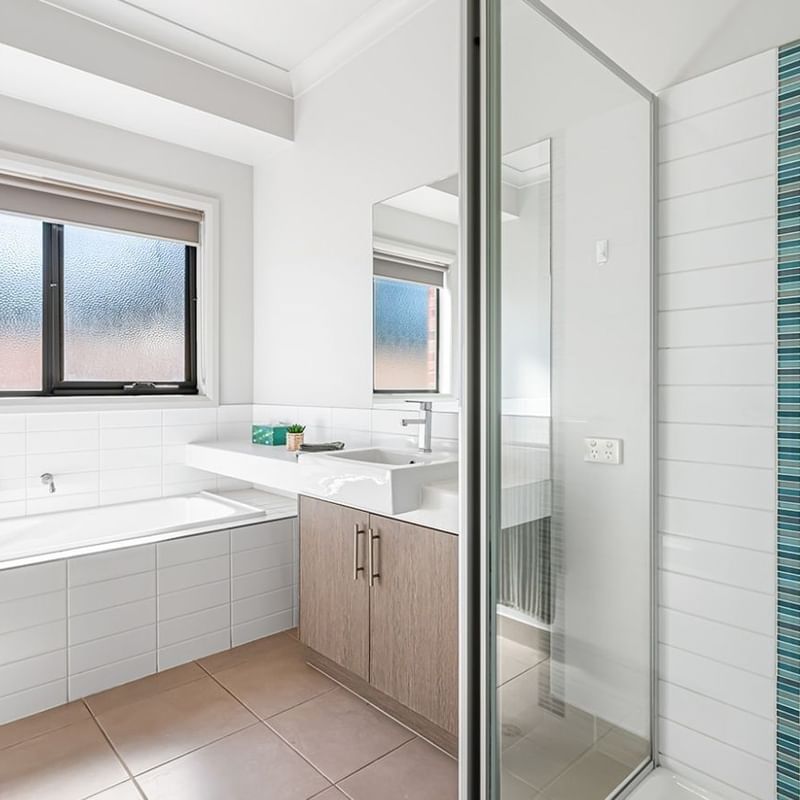 White bathroom with bathtub, sink, and shower at La Trobe University Regional Housing – Mildura.