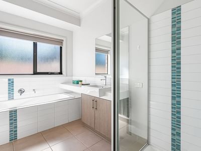 White bathroom with bathtub, sink, and shower at La Trobe University Regional Housing – Mildura.