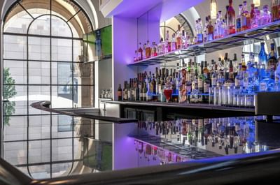Shelves of liquor bottles by the bar counter in Allerton Hotel Lobby Lounge at Warwick Allerton Chicago