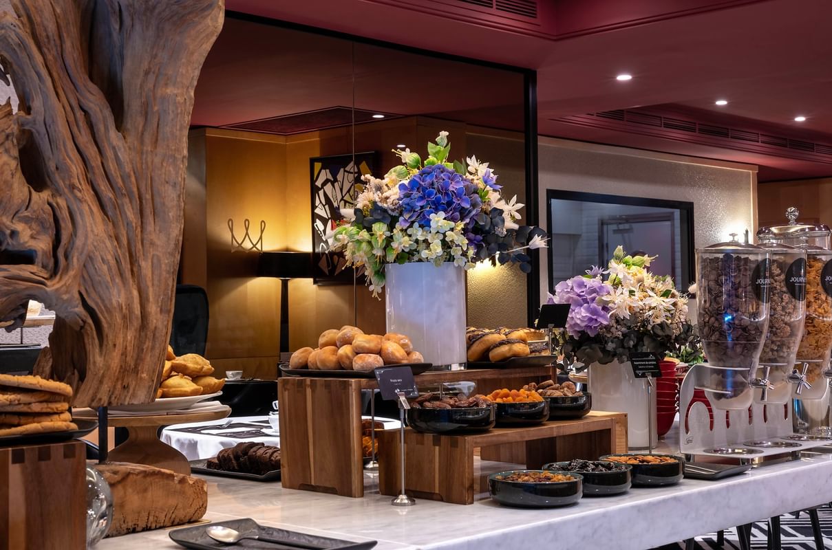 Pastries and nuts by blue hydrangeas under warm light on a marble counter at Warwick Paris Champs Elysées