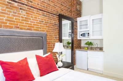 Cozy bed, nightstand & kitchen pantry with mirror in Queen Premiere at Retro Suites Hotel
