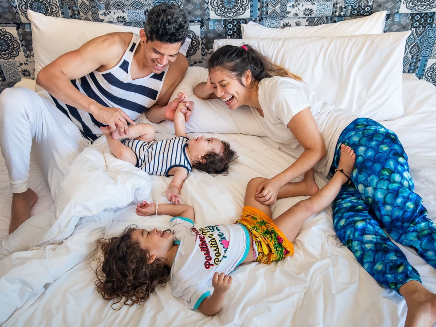 A family of four lying together on a bed while smiling in the room at Hotel Isla Del Encanto