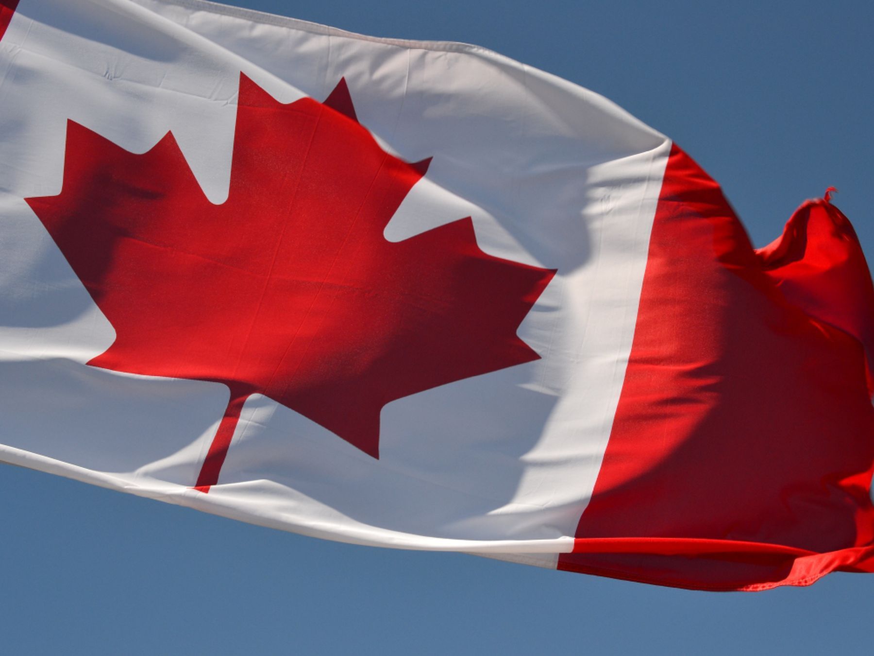 Canadian flag waving against a blue sky near Sandman Hotel & Suites Winnipeg Airport