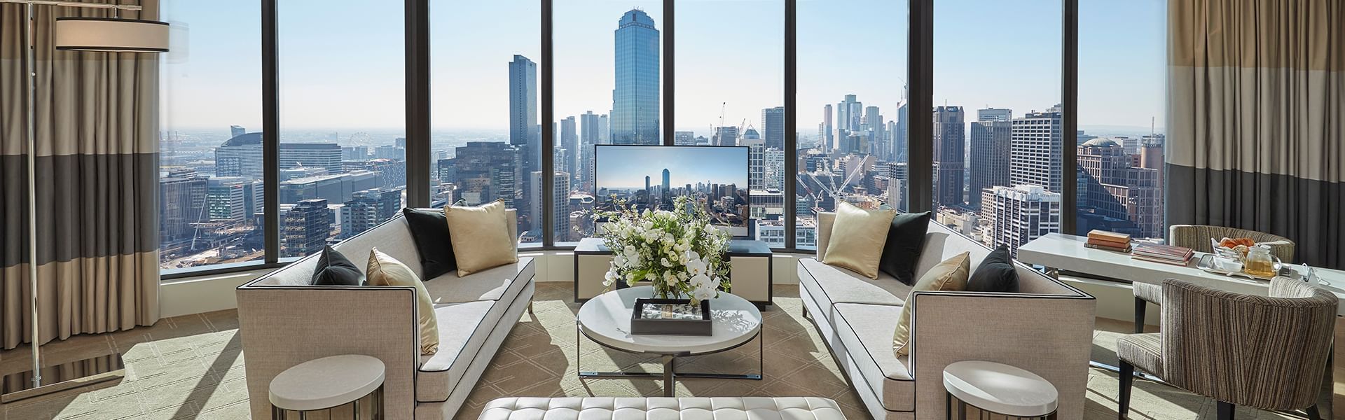 Luxury living room with modern furniture overlooking a city skyline through the windows at Crown Towers Melbourne