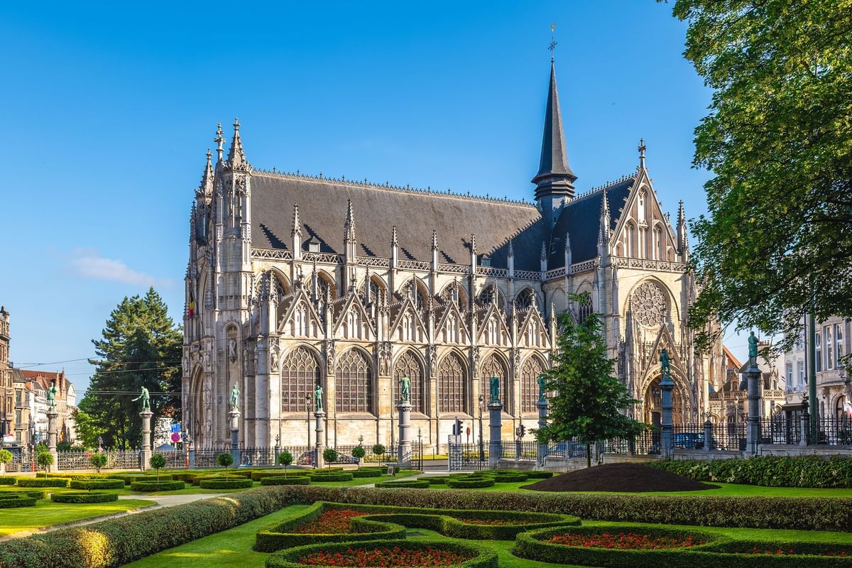 Gothic church with tall spires and stained-glass windows, placed by a manicured park at Warwick Grand Place Brussels