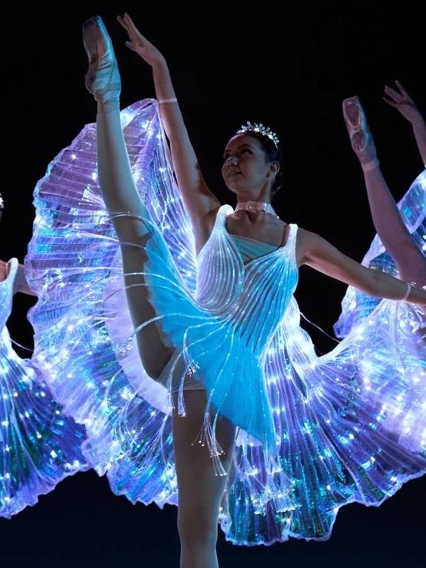Dancers in illuminated costumes perform Ballet of Lights on stage.