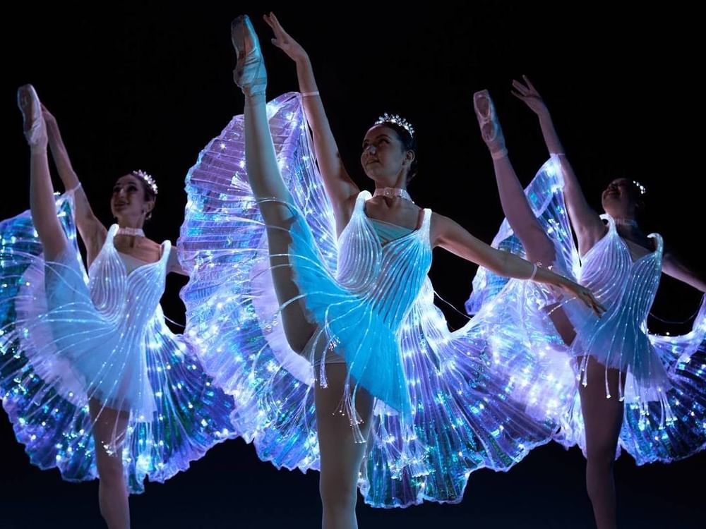 Dancers in illuminated costumes perform Ballet of Lights on stage.