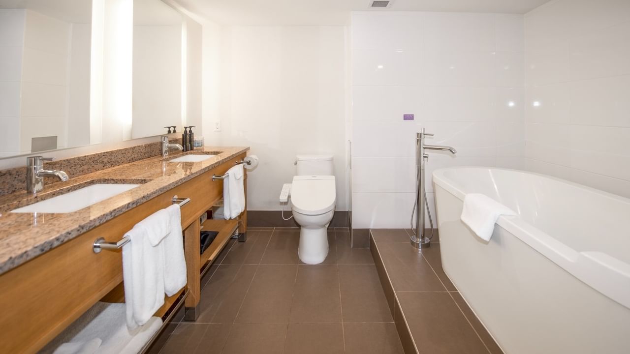 Modern bathroom with two sinks, a toilet, and a bathtub.