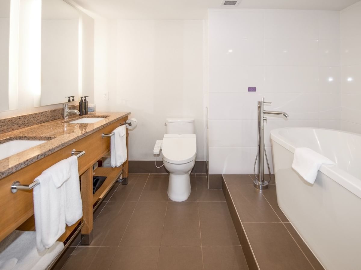 Clean, spacious bathroom with dual sinks, a toilet, and a large bathtub.