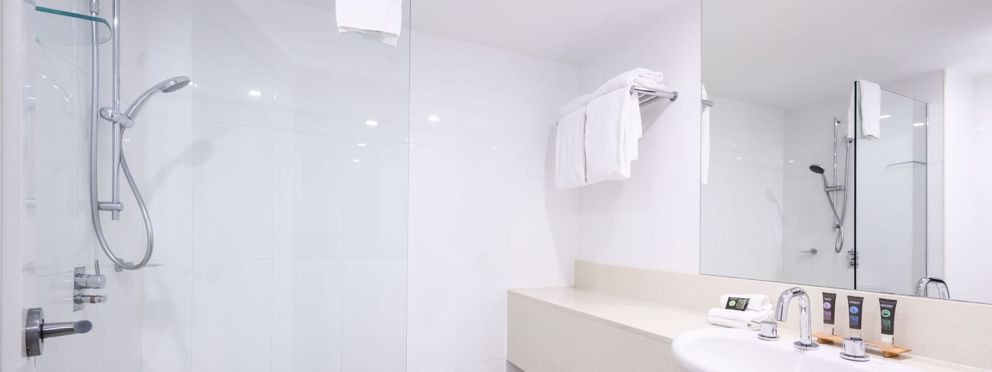 Vanity with various toiletries by the glass shower in Executive Rooms at Novotel Sunshine Coast Resort