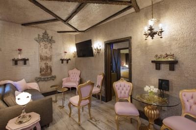 Elegant sitting area featuring pink and gold chairs, a plush sofa, and wall art in Cinderella's Gown at The Roxbury