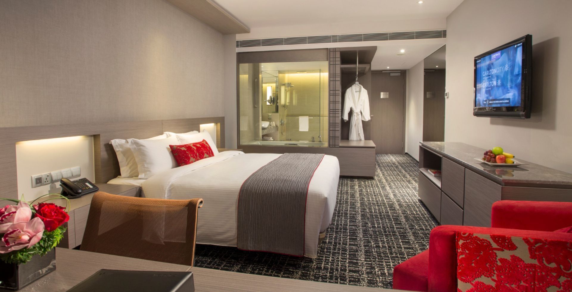 Executive Room with a glass-walled bathroom and a cozy red chair at Carlton Hotel Singapore