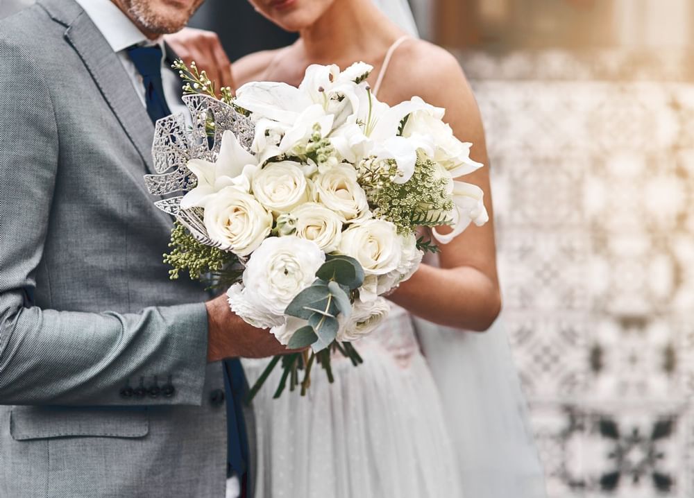 Novia y novio sosteniendo un ramo de flores en Live Aqua Resorts