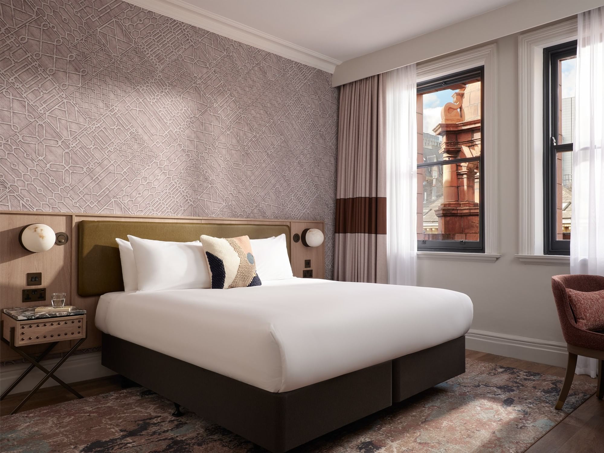 King-sized bed in Premium Double Room with map-patterned wallpaper and large windows at The Met Hotel Leeds, England