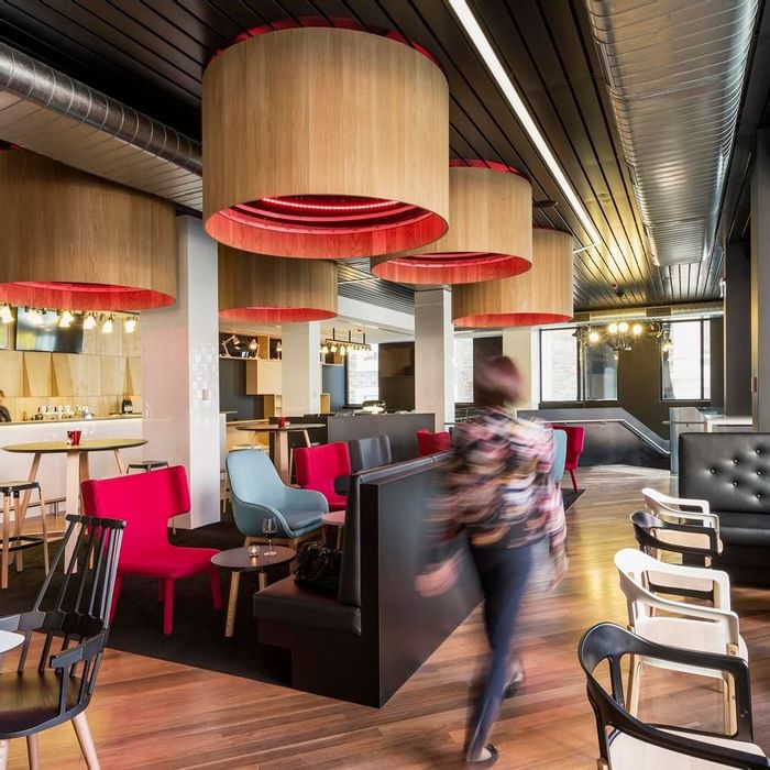 Guest walking through Level One Bar, surrounded by stylish seating and distinctive lighting at Ibis Adelaide