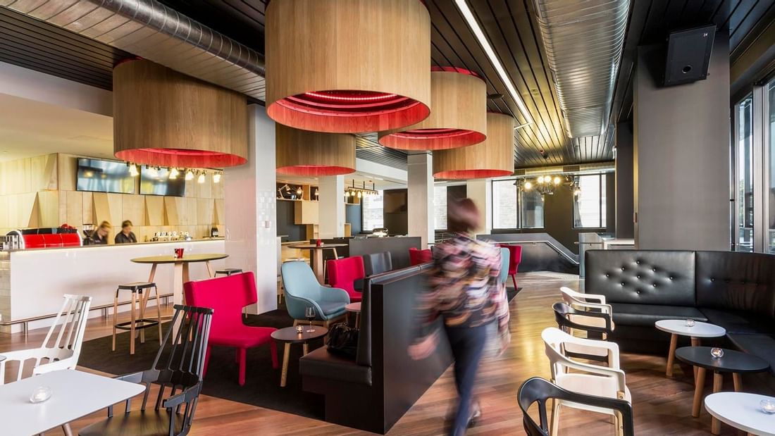 Guest walking through Level One Bar, surrounded by stylish seating and distinctive lighting at Ibis Adelaide