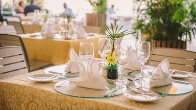 Elegant outdoor dining table with white napkins, wine glasses, and a tropical flower centerpiece at Hotel Montana Haiti