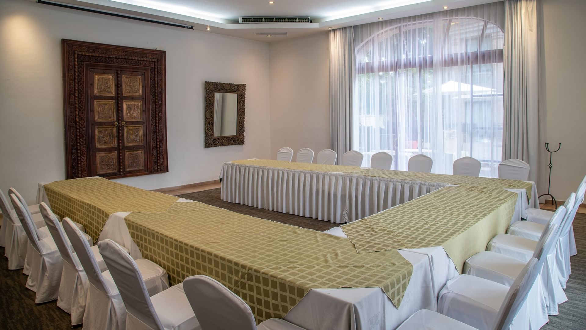 Salón de eventos con mesas en forma de U cubiertas con manteles verdes y sillas blancas en Quinta Real Guadalajara