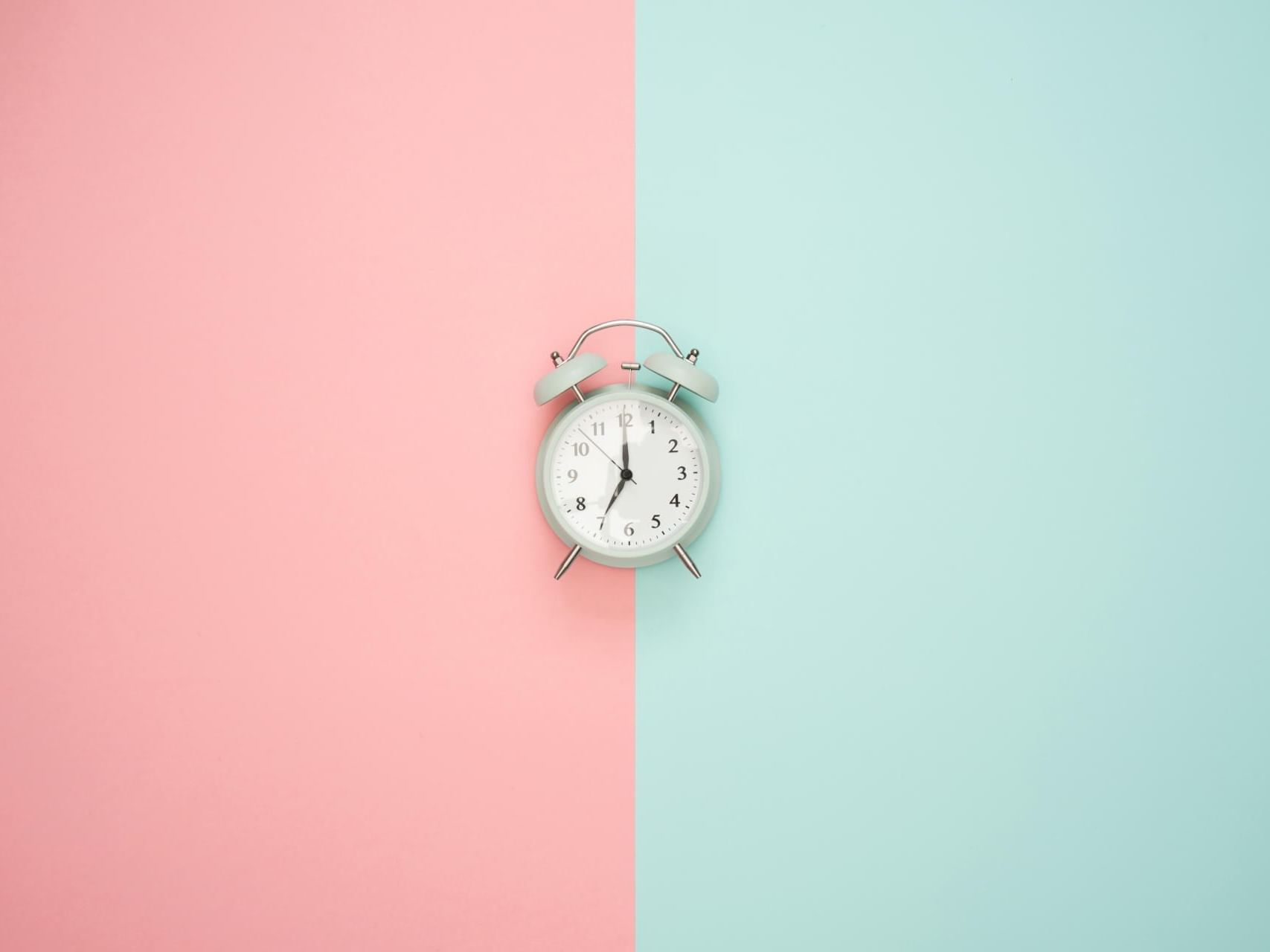 Alarm clock in a pink & blue background featuring Book in advanced at Starling Hotel Lausanne