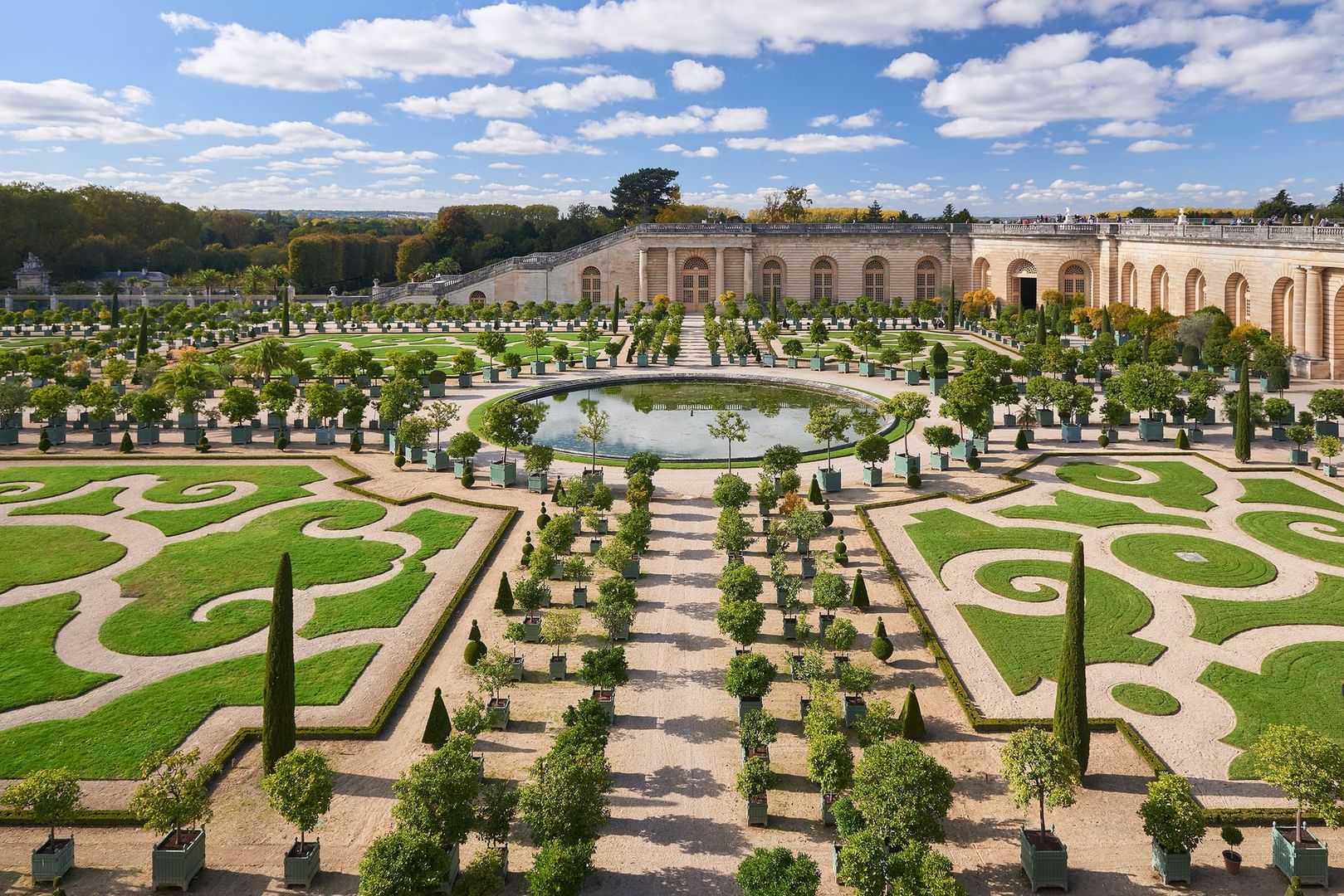 Vue aérienne des jardins à la française avec bassin et orangerie sous un ciel bleu nuageux à Hotel Westminster Warwick Paris