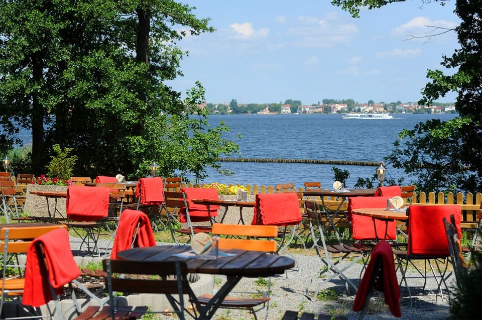 Outdoor dining area with a lake view at Müggelseeperle Hotel