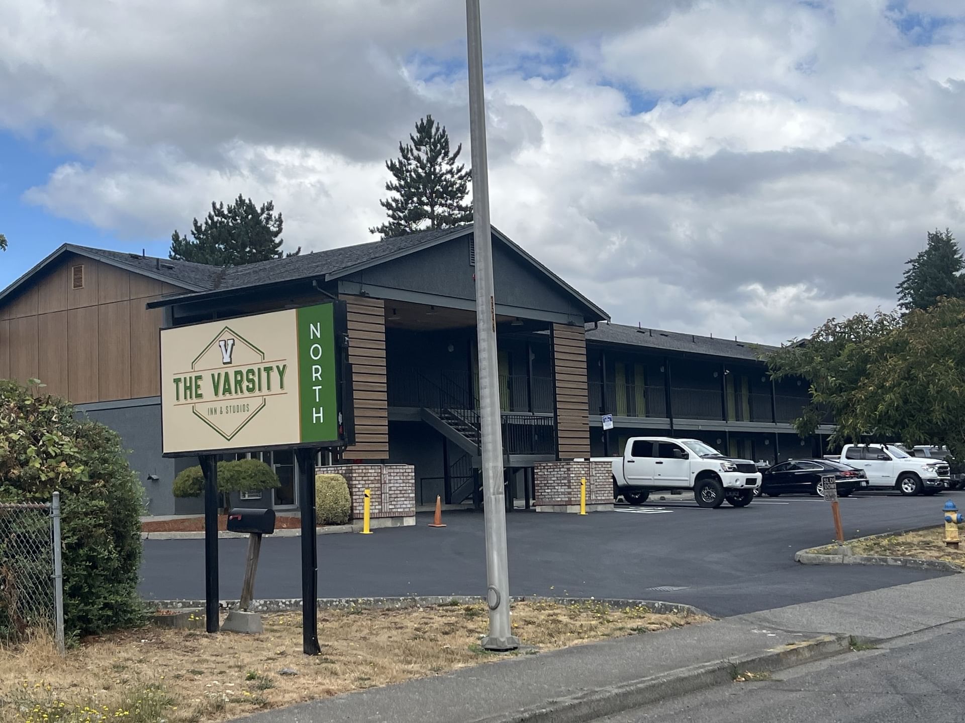 Entrance of The Varsity North with a clean parking lot under a partly cloudy sky, one of the best hotels in Centralia, WA