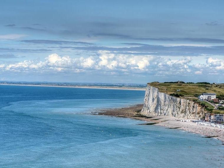 Vue aérienne de la côte maritime avec des falaises et une plage bondée.