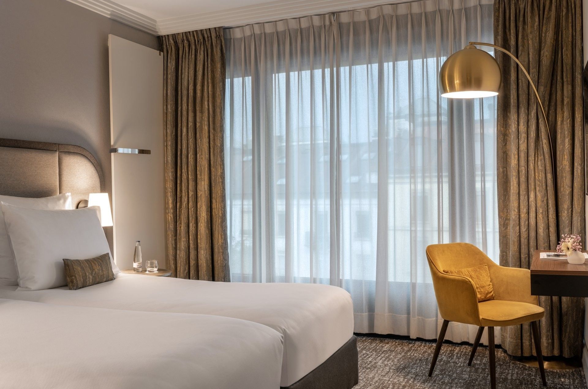 Classic Room with twin beds and a yellow armchair under an arc lamp by a large window at Warwick Geneva