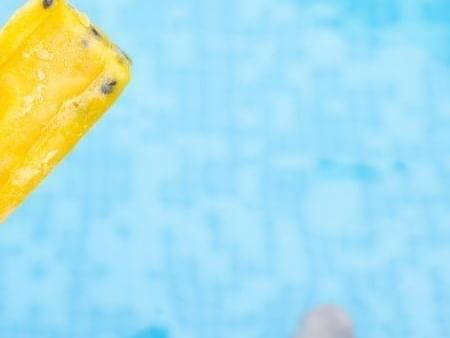 Close-up of person holding a popsicle while lounging in the pool in Palett America at Las Casitas Village