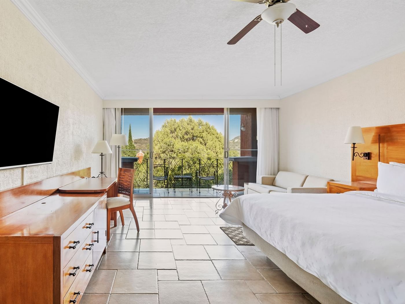 TV with work desk facing bed and a balcony with a scenic green view in Mountain View, 1 King at Fiesta Americana