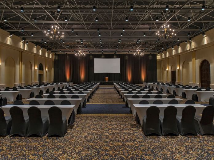 Hacienda Ballroom with chairs and tables arranged neatly facing a screen at Hacienda del Mar Los Cabos